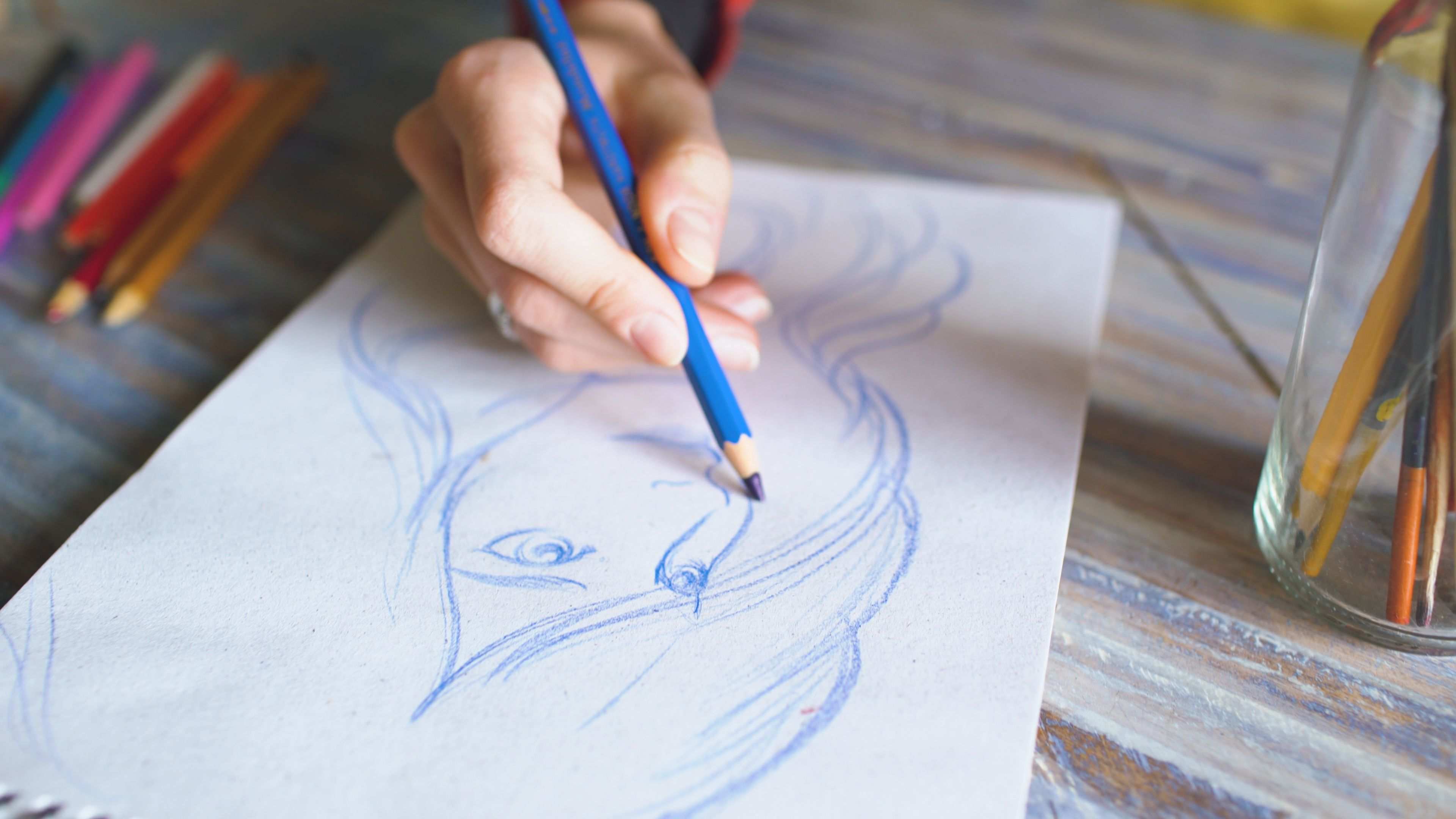 Hand, die mit Buntstiften auf Papier arbeitet — Werkzeuge für handwerkliches Arbeiten.